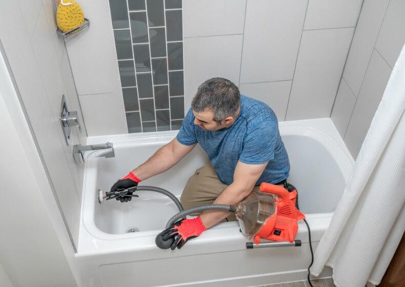 technician using plumbing snake to clear a clogged drain in San Quentin